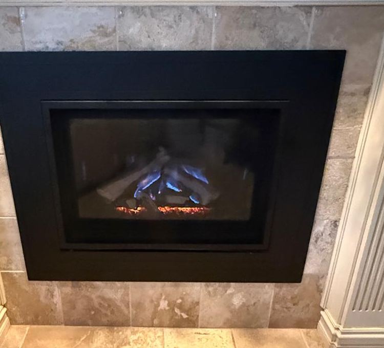Gas fireplace with blue flames behind glass in a stone tile surround